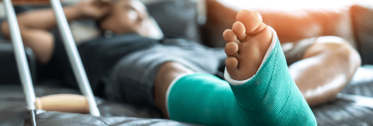 1200x406_man lying on couch with foot in cast man lying on couch with foot in cast