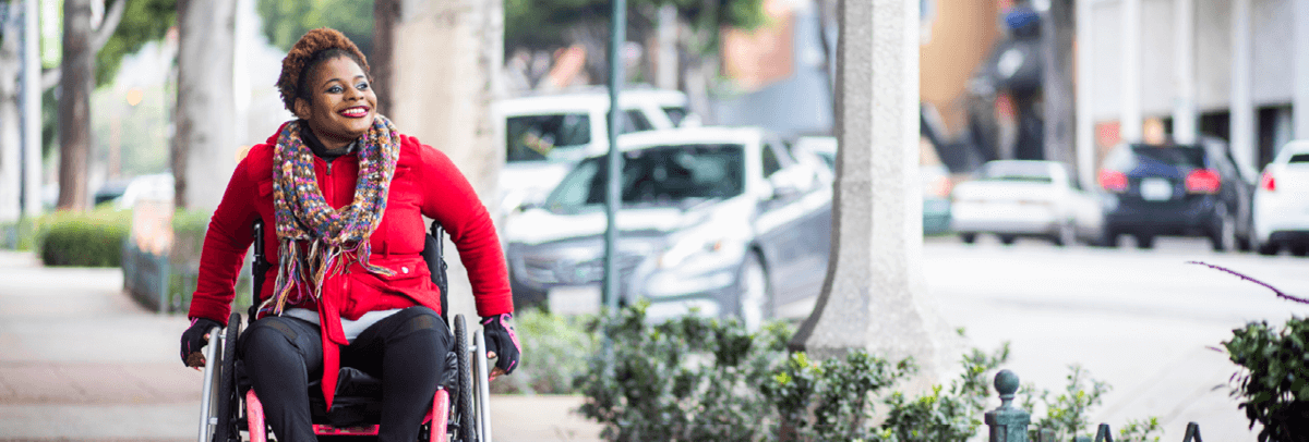 1200x406_woman in wheelchair traveling along sidewalk woman in wheelchair traveling along sidewalk
